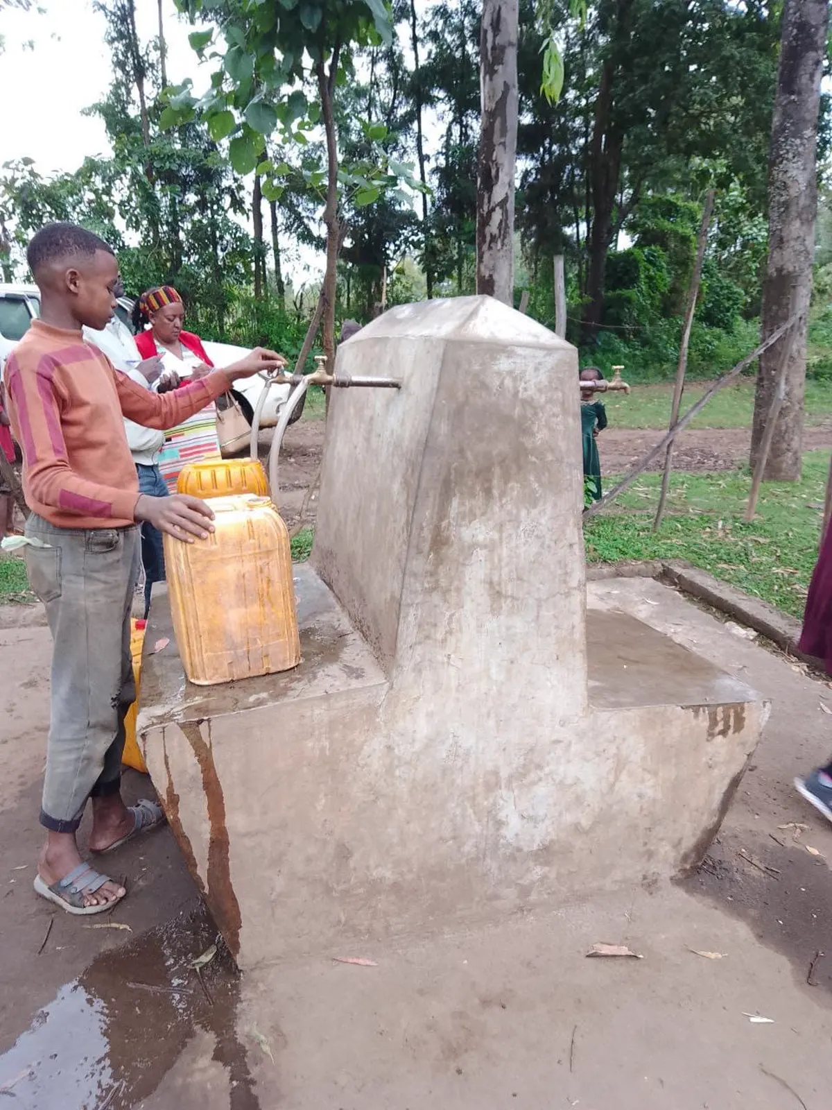 Community member collecting water from a completed public water point